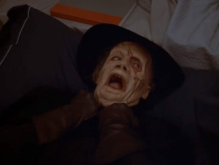 The Phantom lays in the bed with his tight grip pinned at his throat