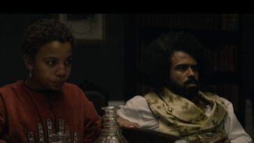 Onion (Joshua Caleb Johnson) and Daveed Diggs looking forlorn while holding empty glasses, sitting on a couch in a dark room