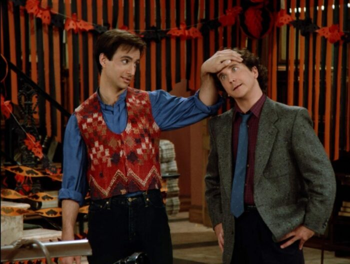 Balki in a multi-colored vest places his left hand on his cousin Larry who has his eyes crossed like he's under his control
