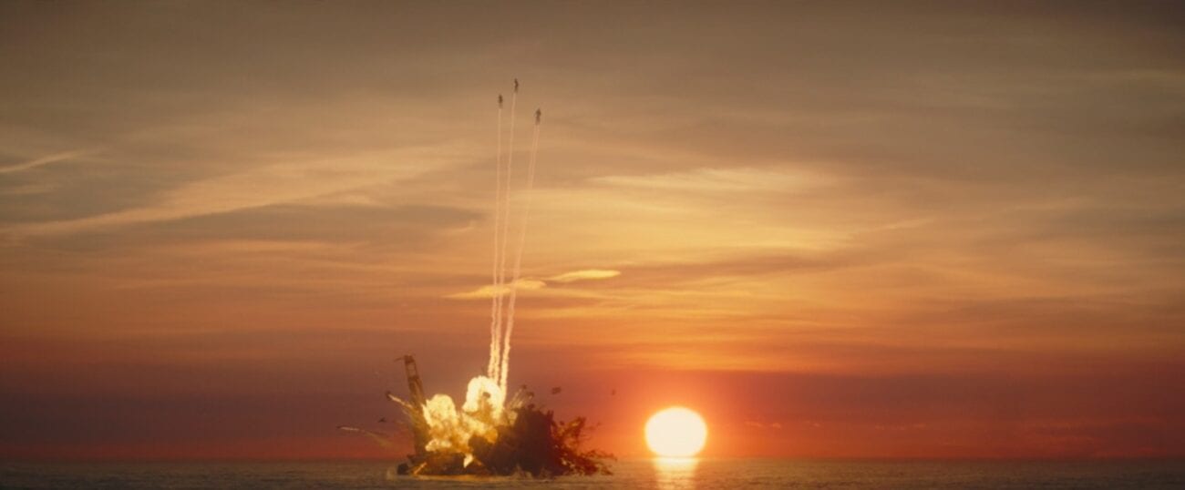 Three Mandalorians fly from the Quarren ship as it blows up, with a sunset in the distance