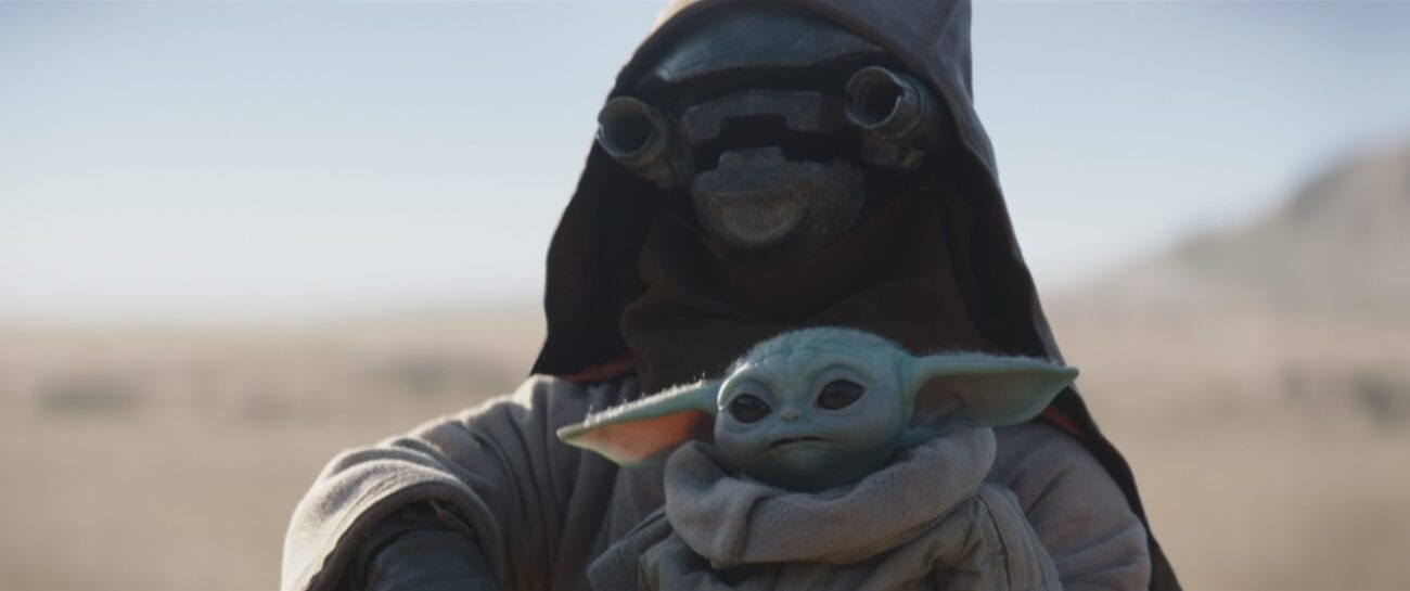 A scrapjaw alien holds The Child (Baby Yoda) threateningly