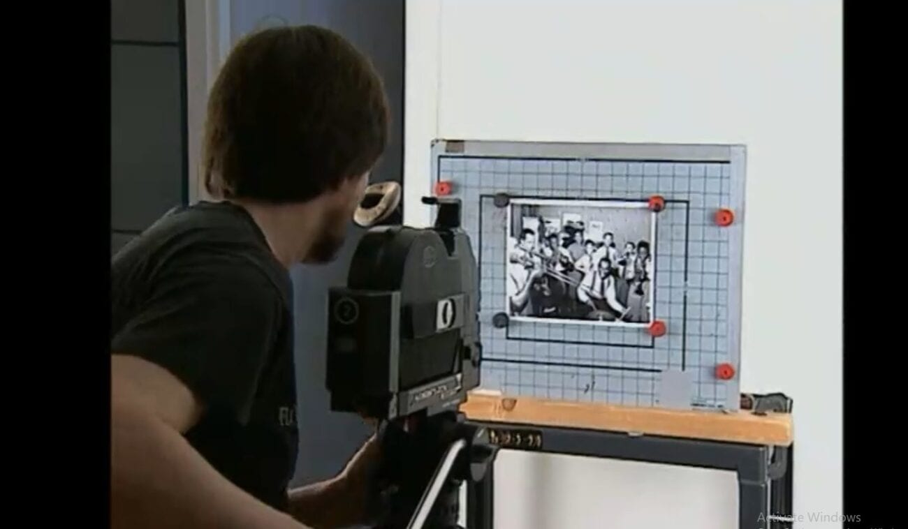 Ken Burns holds a camera on tripod pointed at a photograph set to be scanned