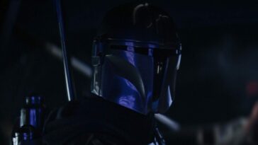 Mando in the cockpit of an Imperial Shuttle, with his armor reflecting blue lights