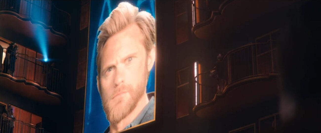 Flagg's face on a large jumbotron screen in a hotel interior in The Stand Episode 5