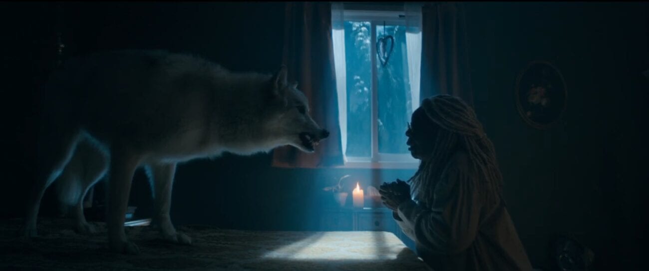 The Stand S1E5 - Mother Abagail sits at a table in the dark, a large gray wolf facing her on the table, snarling