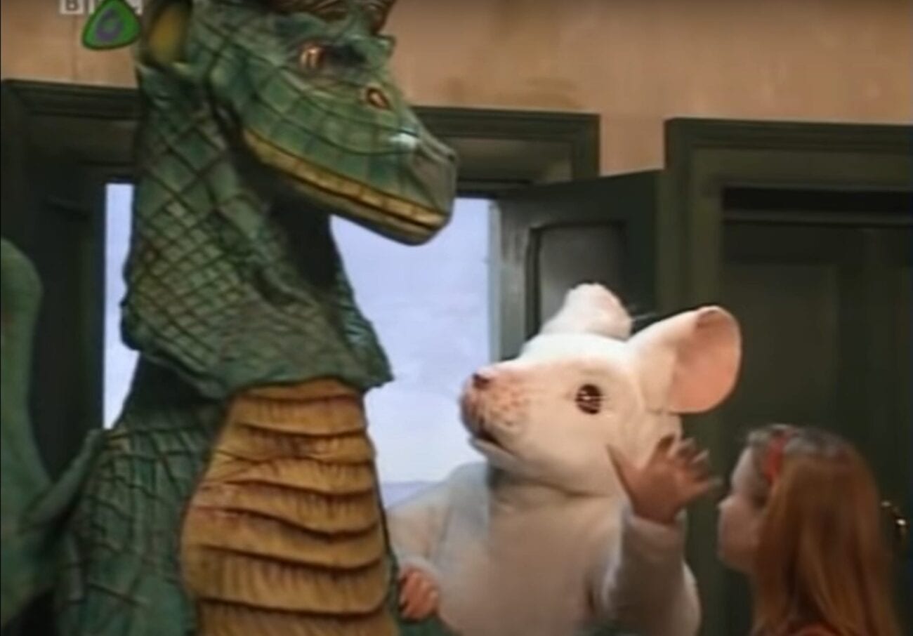 A mouse looks up at a dragon as a girl looks on