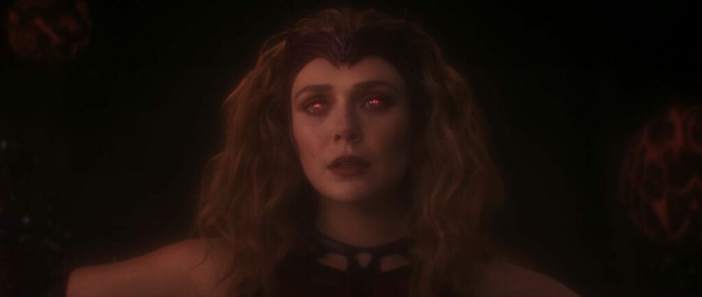 A close-up of the Scarlet Witch's face, absent of humanity, and eyes glowing red.