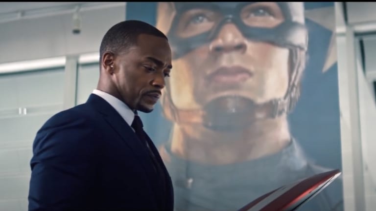 Sam Wilson (Falcon) reckons with Steve Rogers' legacy as he stands in front of a mural of him and looks down at the Captain America shield