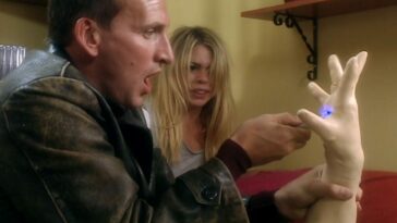 The Doctor uses his sonic screwdriver on a plastic hand as Rose looks on