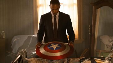 The Falcon looks down at the Captain America shield on a table