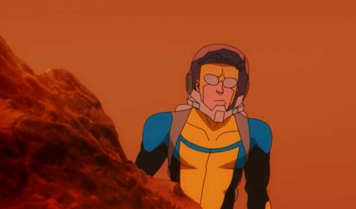 Invincible on Mars. He is standing behind a rock while wearing a light space helmet.