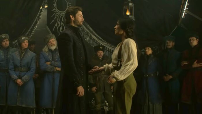 General Krigan (Ben Barnes) and Alina (Jessica Mei Li) stand looking at each other in front of a group of 2nd Army troops