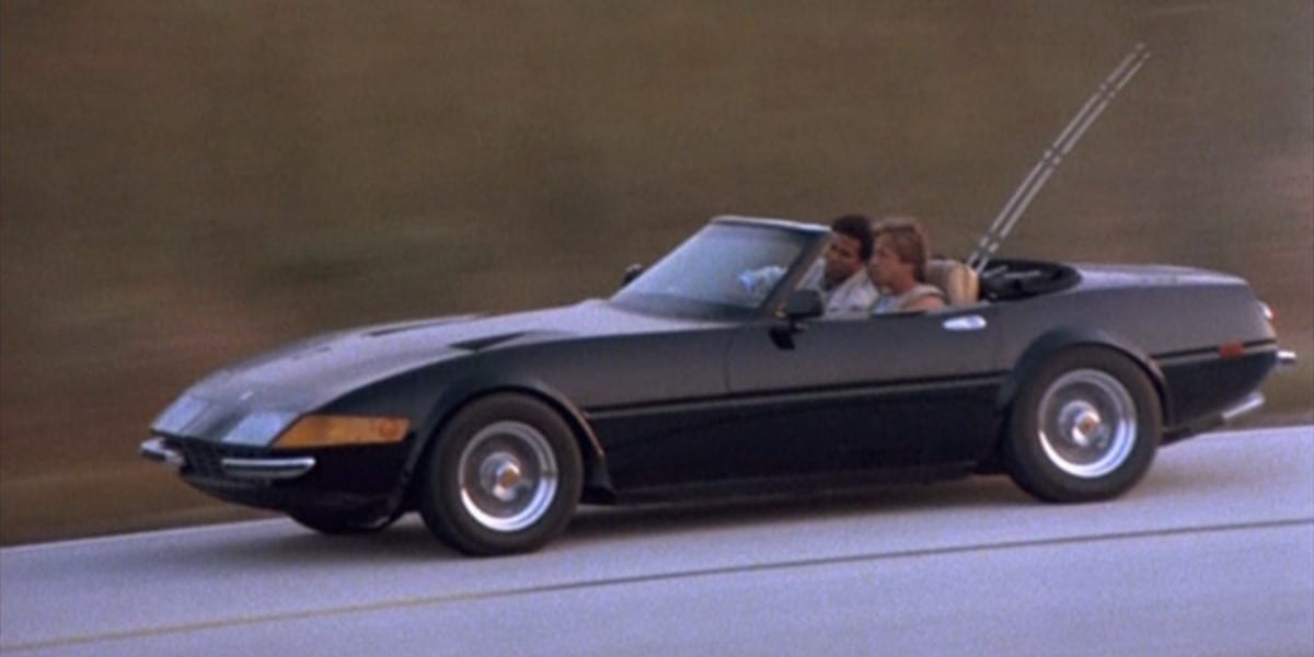 Crockett and Tubbs riding in black Ferrari, with fishing poles in the back of the car in TV show Miami Vice