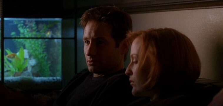 Mulder and Scully sit on a couch next to a fish tank