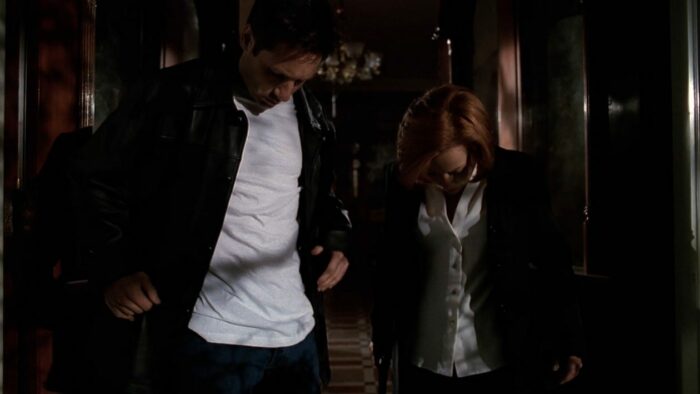 Mulder and Scully look down at their clothes in confusion as they leave the haunted house in The X-Files Season 6