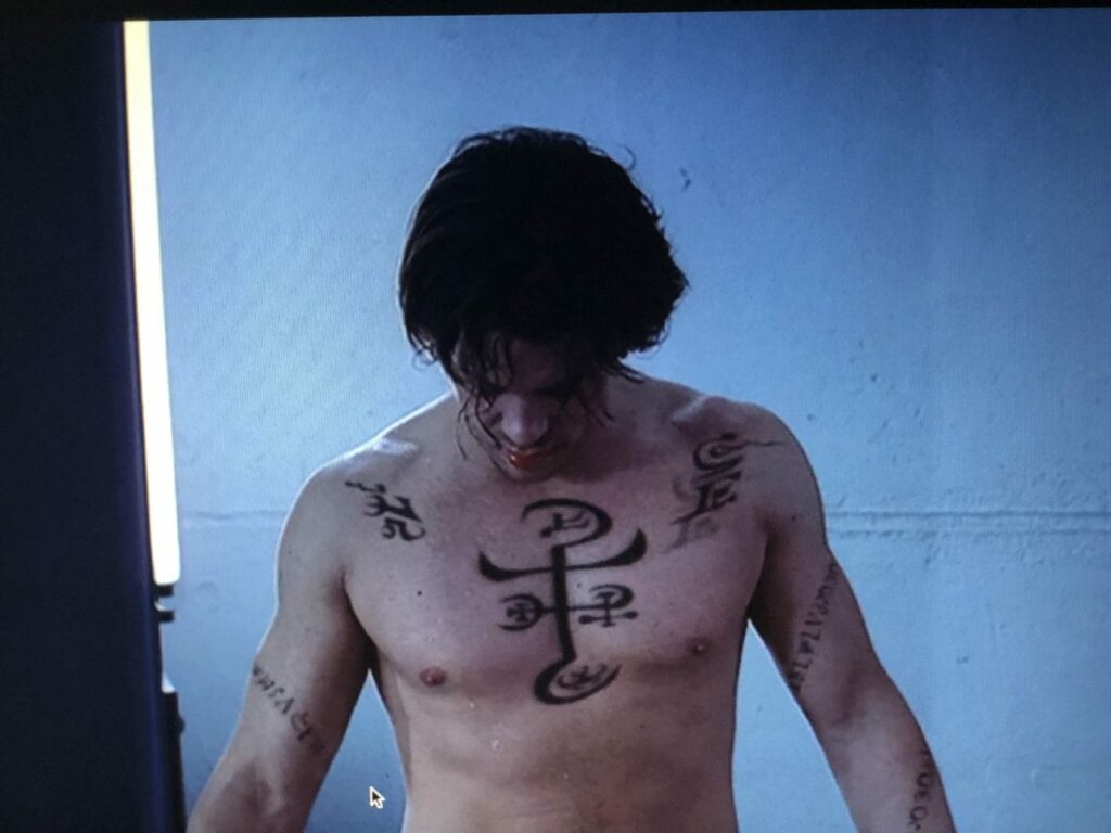 Lindsey, shirtless, watches as his mystical tattoos disappear