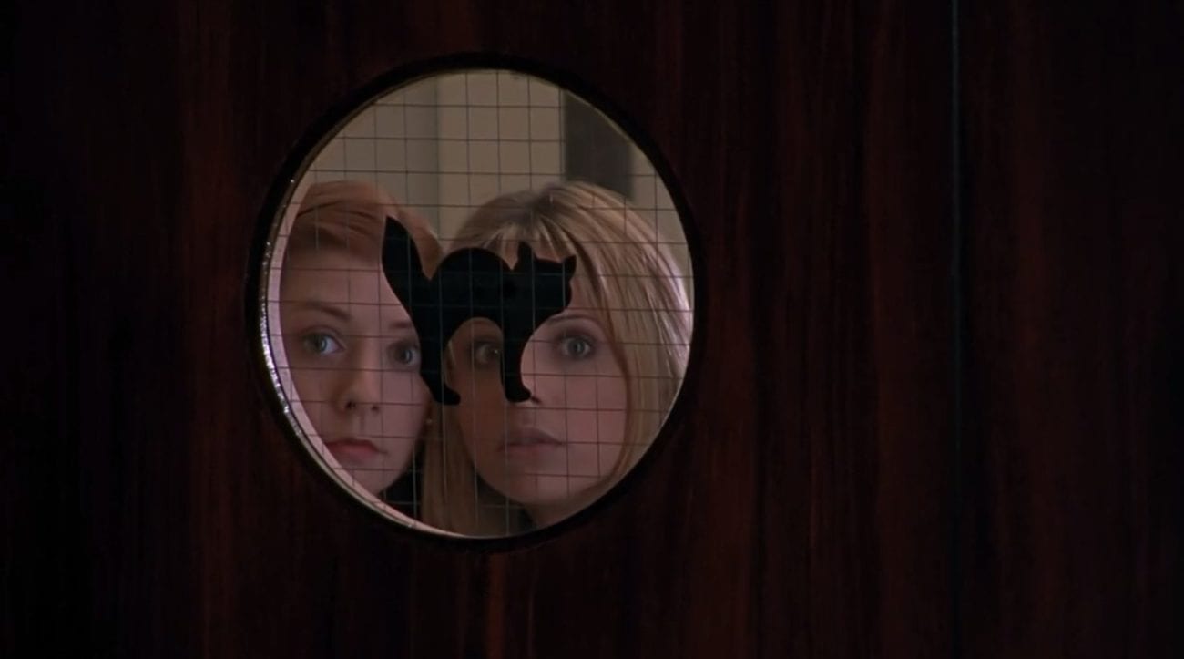 Willow and Buffy peering into a round window with a black cat on it