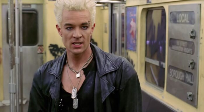 Spike, in 70s grunge eyeliner and dog tags, puts on his iconic black coat for the first time.