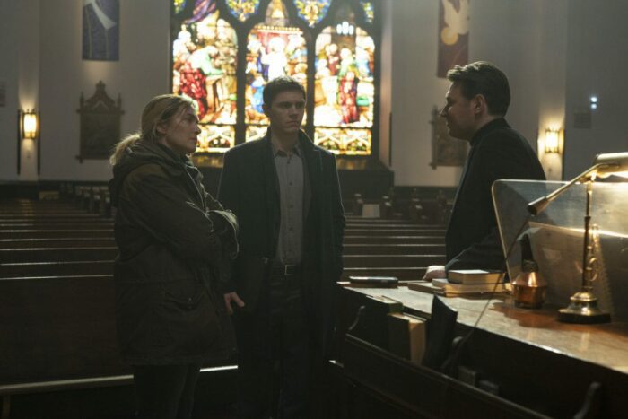 Mare (Kate Winslet) and Detective Zabel (Evan Peters) interrogate Deacon Burton (James McArdle) in a church