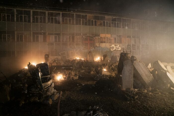 Fire around rubble with a graffittied building in the background in The Nevers S1E6