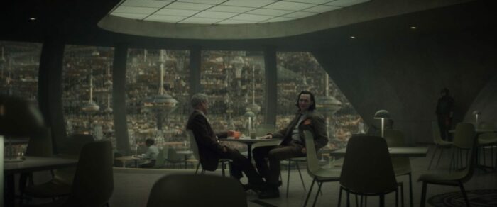 Agent Mobius (left) and Loki (right) sit in a cafeteria and discuss the Sacred Timeline.