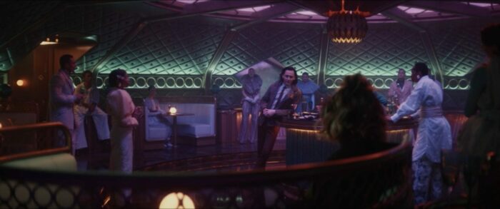 Loki stands in the middle of the bar, serenading drunk passengers in Asgardian.
