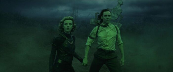 Sylvie (left) and Loki (right) hold hands in green mist and stare at the portal they just enchanted.