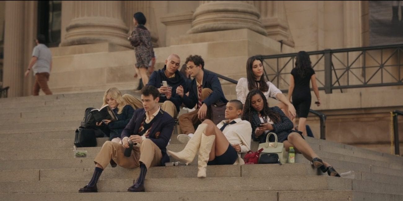 A group of teenagers dressed in monochrome and brown-toned school attire shitting on the steps of their large New York City high school.