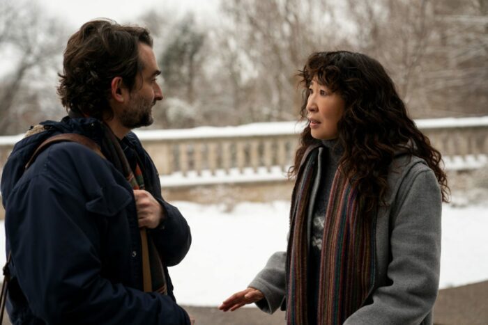 Ji-Yoon (Sandra Oh) and Bill (Jay Duplass) standing in front of a snowy wall looking at each other