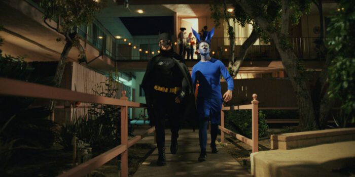 Victor dressed as Batman and Josh dressed as Arrow, strutting down a walkway outside an apartment complex