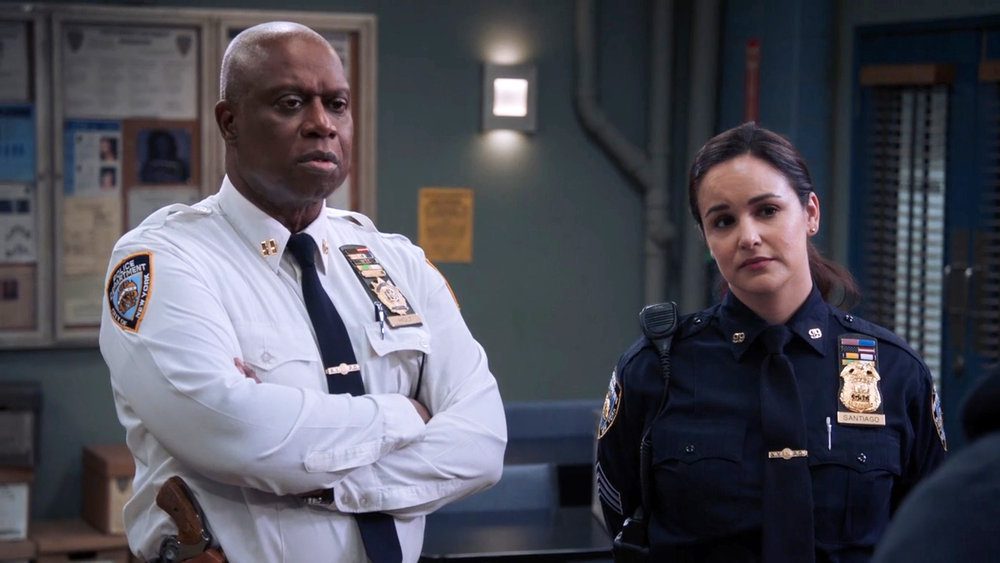 Holt stands next to Amy, arms folded