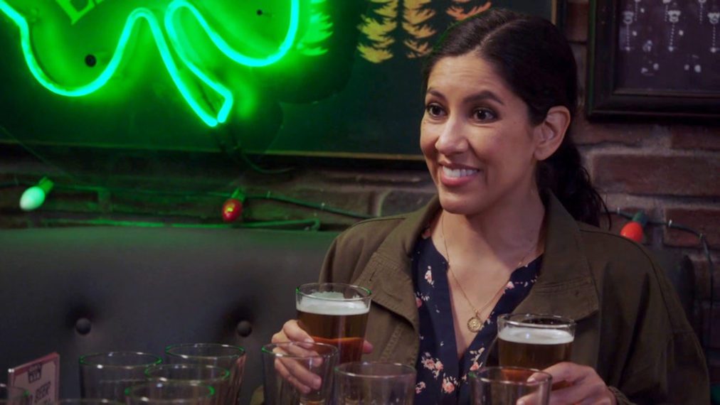 Rosa sits at the bar, holding two beers