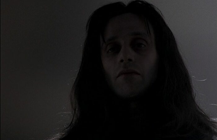 A sinister man with long dark hair