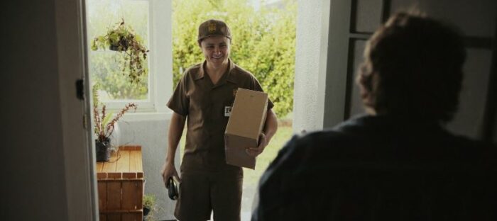 Victor in his UPS uniform, with a package under his arm, smiling as a customer opens the door