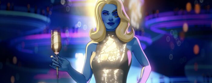 Nebula (Karen Gillan) with long blonde hair and a sparkly dress, stands holding a drink in front of a neon background
