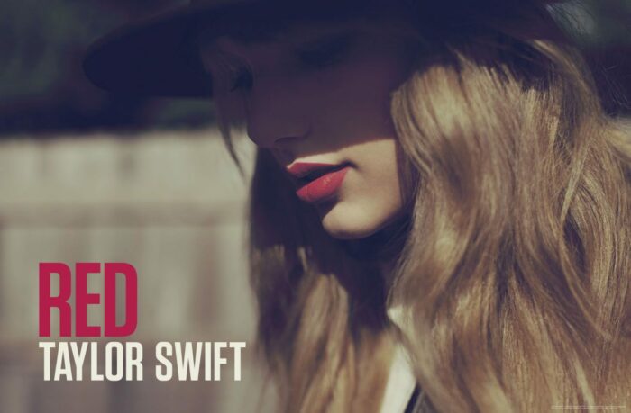 RED album cover features Taylor Swift in a hat looking downwards, her face half in shadow