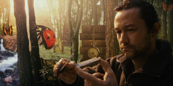 Josh whittles a piece of wood as he sits in a forest with a large animated ladybug on a tree beside him