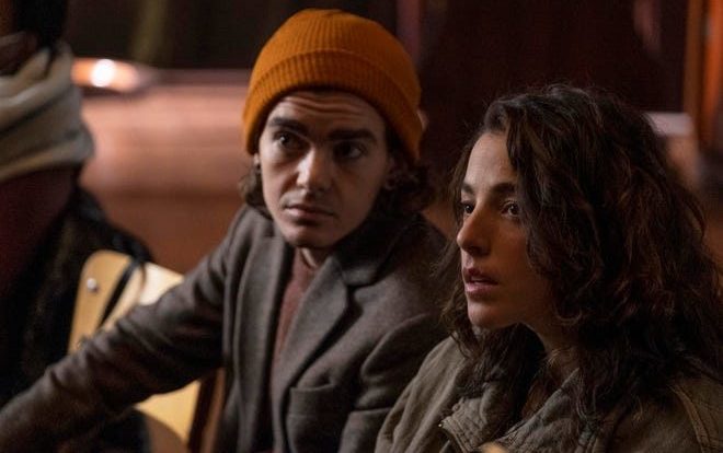 Sam (Elliot Fletcher) and Hero (Olivia Thirlby) look to the left with an orange light behind them