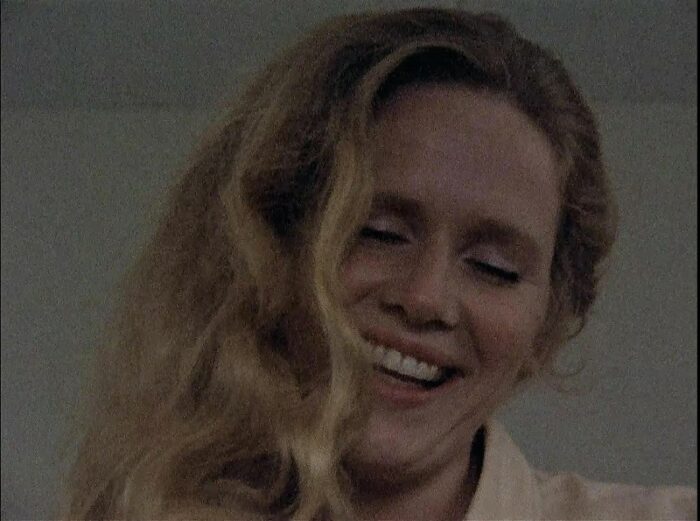 In this image from the 1973 series Scenes from a Marriage, Marianne (Liv Ullmann) is depicted smiling, in close-up, with her eyes nearly closed and hair down.