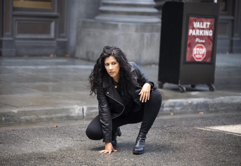 Rosa crouches on the street