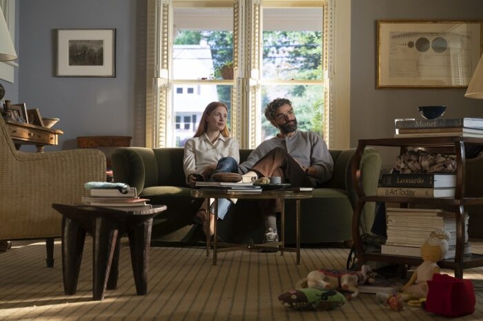 In this image from the 2021 remake of Scenes from a Marriage, the characters MIra (Jessica Chastain) and Jonathan (Oscar Isaac) are depicted being interviewed in their living room. 