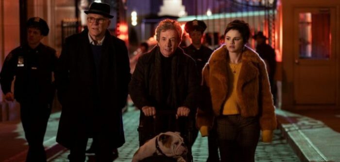 Charles (Steve Martin), Oliver (Martin Short), and Mable (Selena Gomez) Stand next to each other on a city street at night, police in the background, Oliver is pushing a cart holding Winnie the bulldog