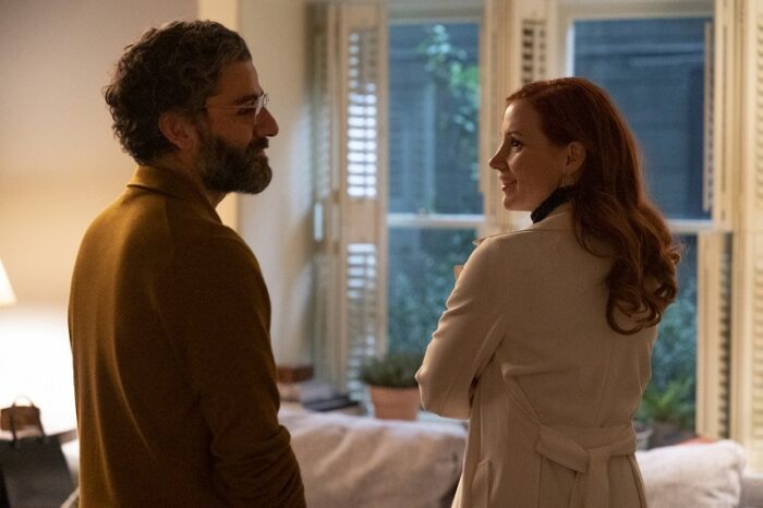In this image from Scenes from a Marriage, the characters of Jonathan (Oscar Isaac) and Mira (Jessica Chastain) smile as they face each other in front of a window in their living room.