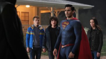 Superman stands between a villain in front of him and his family behind him near their rural home's porch.