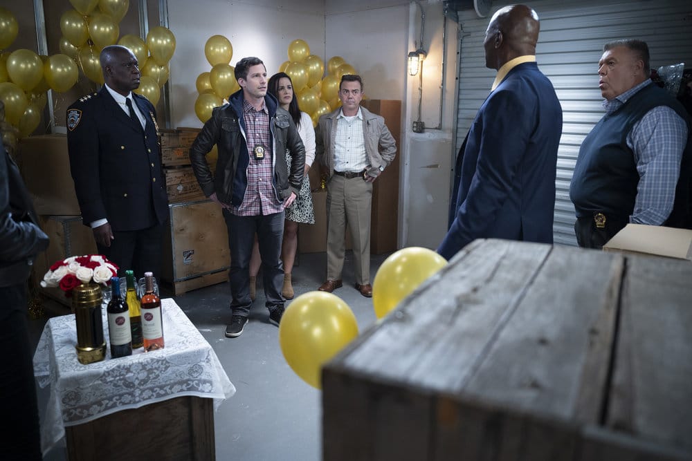 From left to right: Holt, Jake, Amy, Charles, Terry, and Scully locked in the storage unit with golden balloons around them