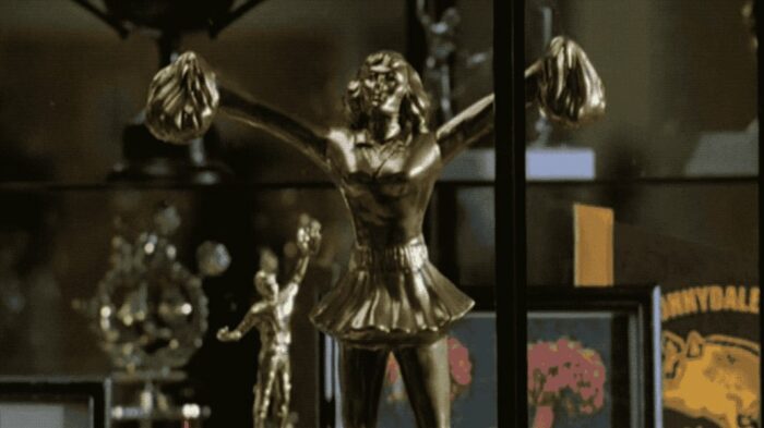 Bronze cheerleader trophy from 'Witch' in a cabinet in Sunnydale High