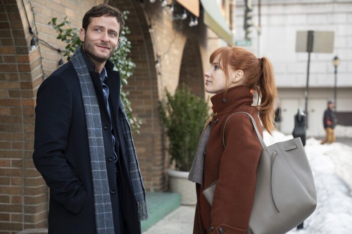 In this image from Scenes from a Marriage Episode 5, Michael Iloni (Poli) and MIra (Jessica Chastain) stand together outside a restaurant, she looking at him and him offscreen, both dressed in overcoats and scarves.