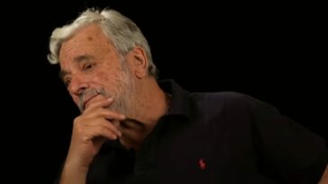 Stephen Sondheim puts a hand to his chin while wearing a black shirt during a NY Times interview