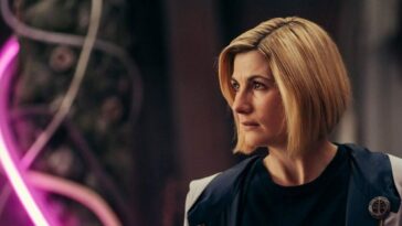 The Doctor (Jodie Whittaker) looks to her right in front of a purple glowing section of the Division Headquarters