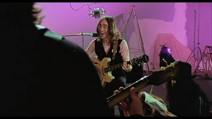 John Lennon smiles playing the guitar
